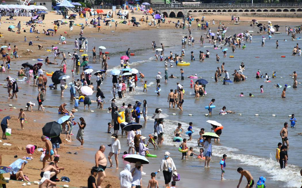 People cooling off on a beach amid hot weather in Qingdao, in China's eastern Shandong province on 1 August 2022.