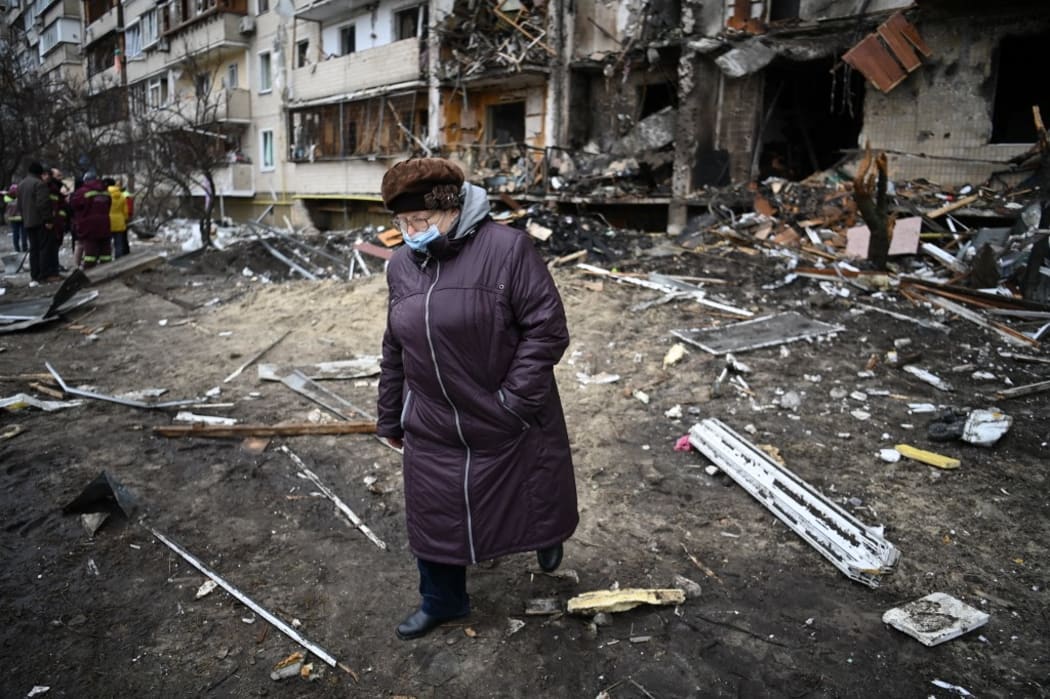 A woman walks in front of a damaged residential building at Koshytsa Street, a suburb of the Ukrainian capital Kyiv, where a military shell allegedly hit, on February 25, 2022.