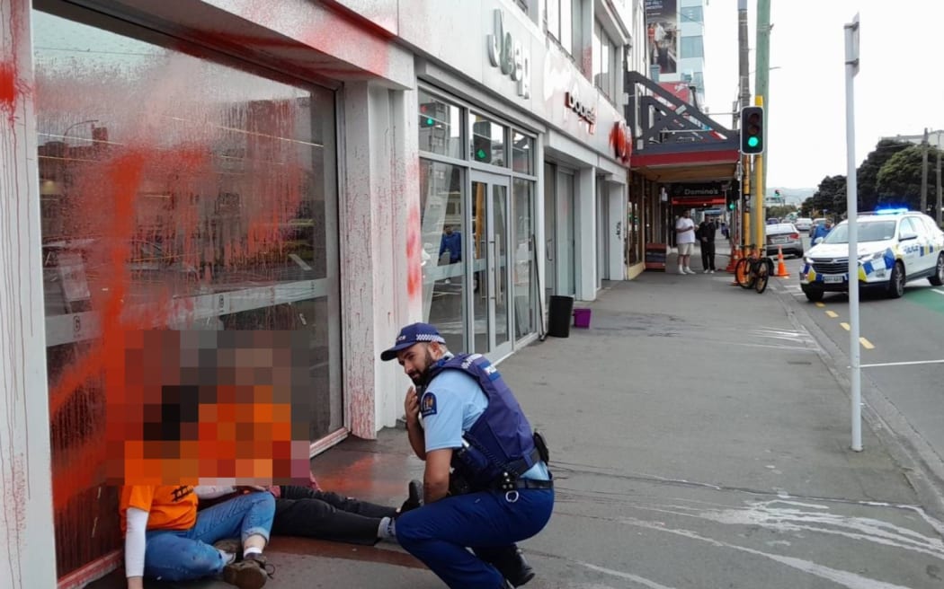 Protesters talk to police outside a car dealership in Wellington