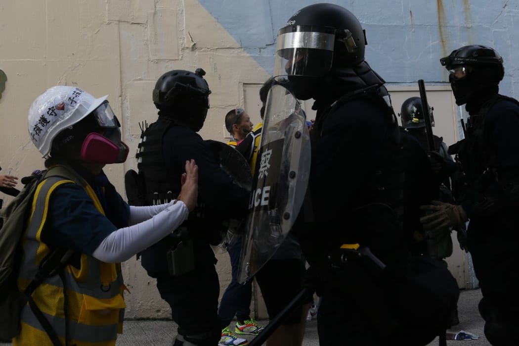 An elderly woman tries to stop riot police from chasing protesters in industrial district Kwun Tong, Hong Kong, on Saturday Aug 24, 2019.