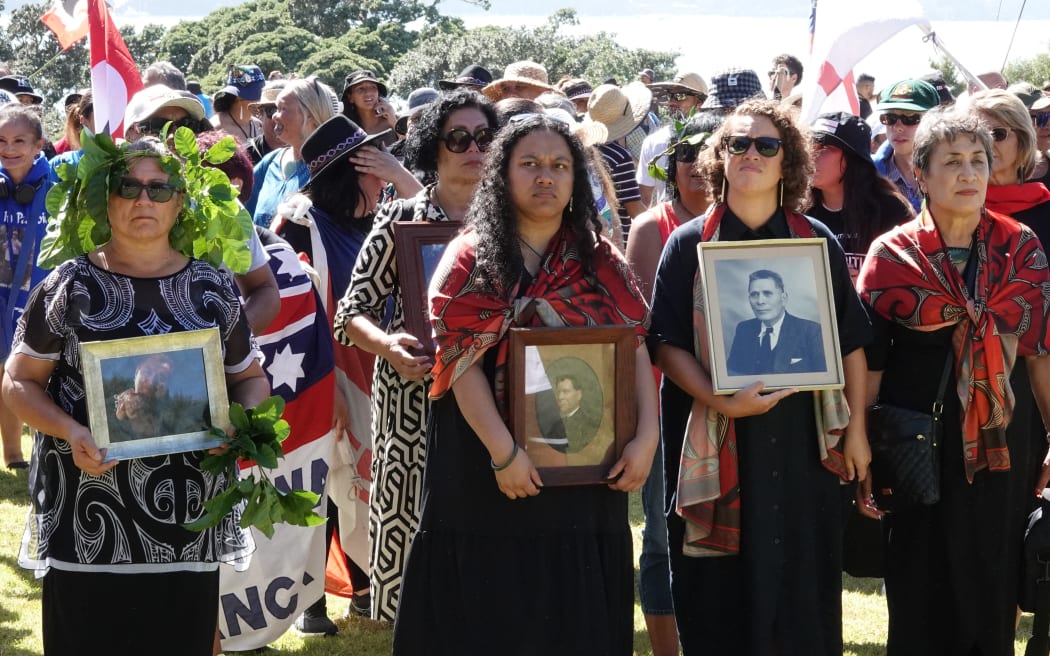 Marchers on the hīkoi carry photo of those who have passed on.