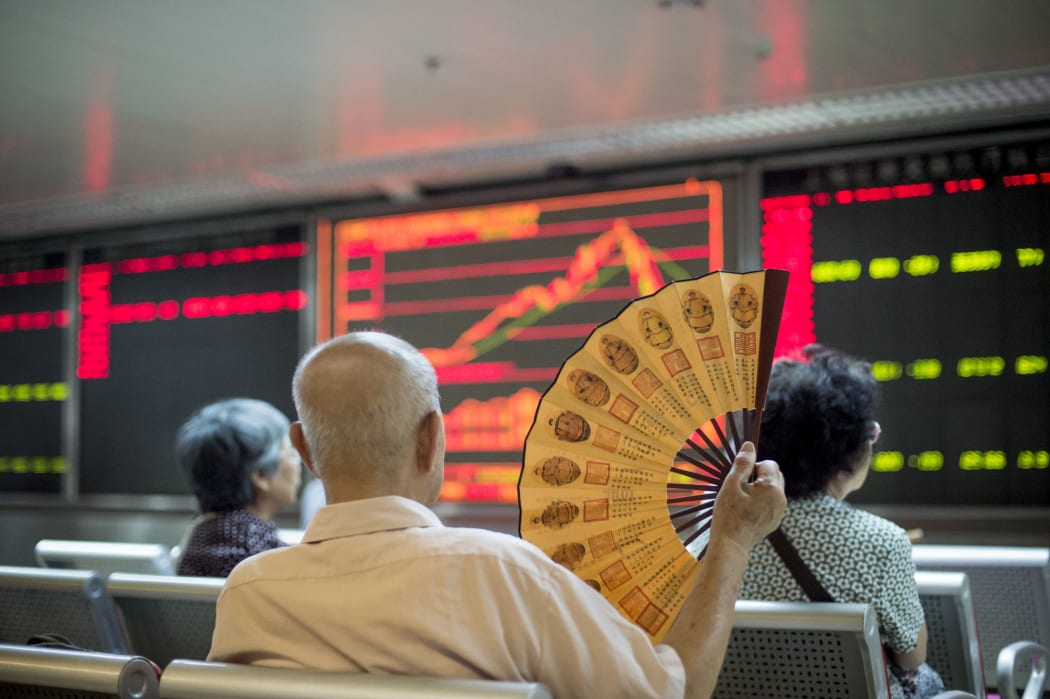 Investors look at screens showing stock market movements at a securities company in Beijing.