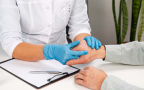 A dermatologist wearing gloves examines the skin of a sick patient. Examination and diagnosis of skin diseases-allergies, psoriasis, eczema, dermatitis.