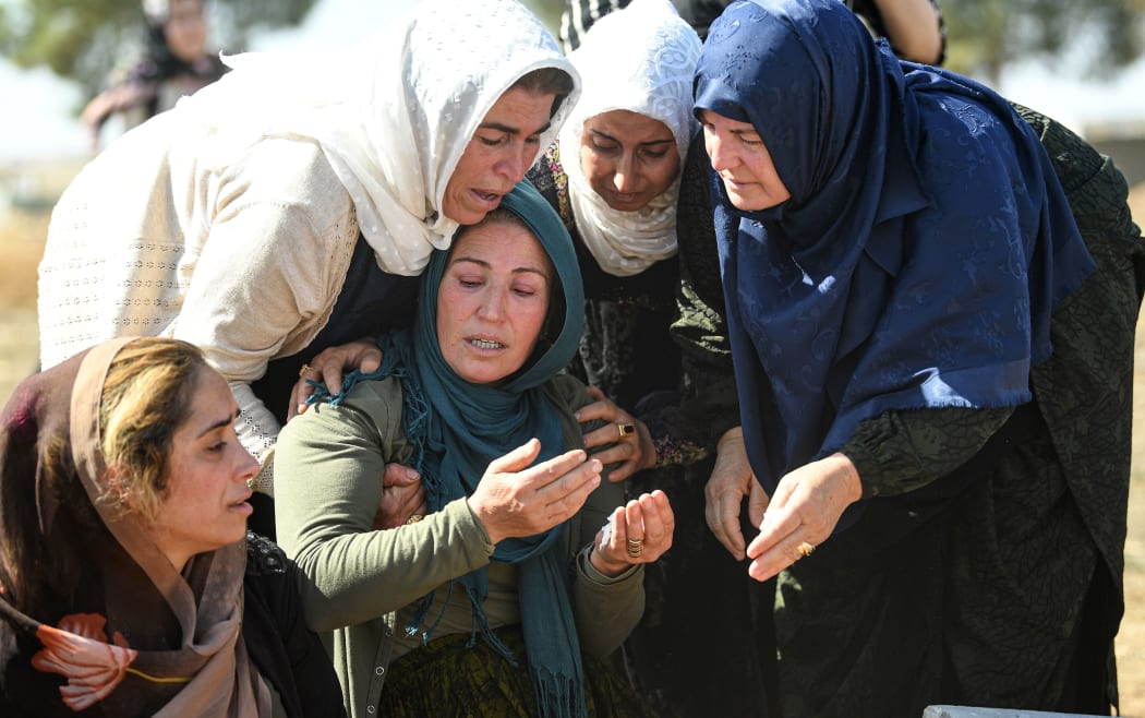 Relatives mourn in front of the grave of Halil Yagmur who was killed in a mortar attack a day earlier in Suruc near northern Syria border, during funeral ceremony in Suruc on October 12, 2019 .
