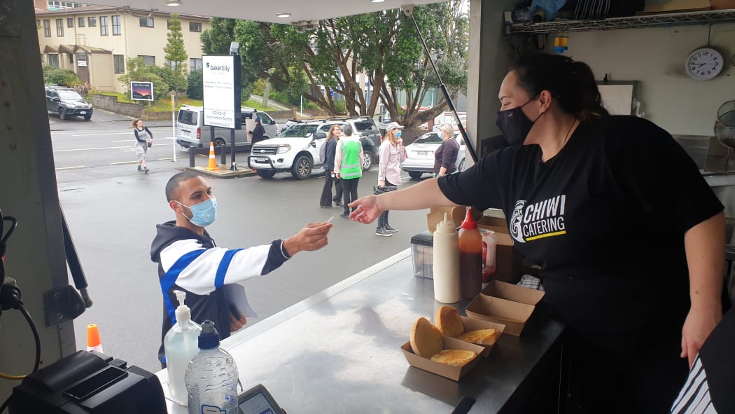 Ashley of Chiwi Catering serving a customer at the bacon buttie vaccination event in New Plymouth