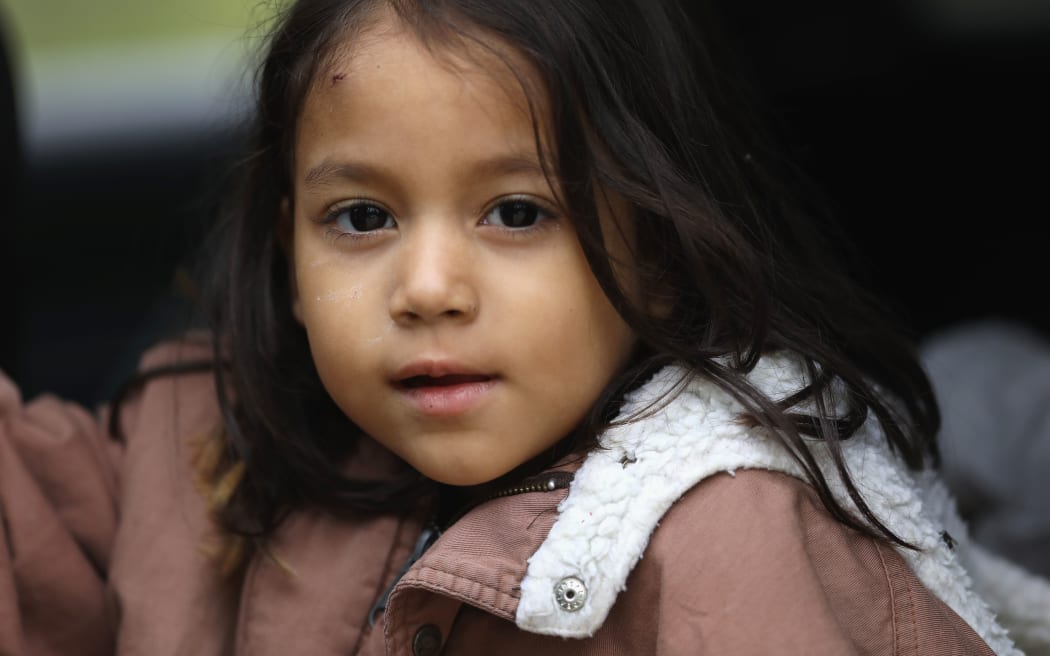 A Honduran immigrant child awaits transport by US Border Patrol agents after crossing with her family into the United States from Mexico.