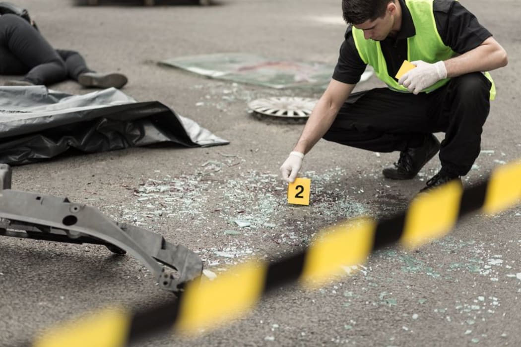A policeman inspects a road after a crash.