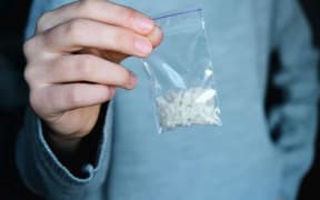 hand holds packet with white narcotic - cocaine, meth or another drug closeup