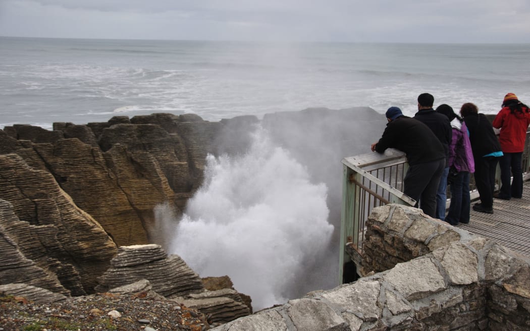 Tourists enjoy the main blowhole in action at the Pancake Rocks, Punakaiki