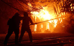 ALTADENA, CALIFORNIA - JANUARY 08: Los Angeles County firefighters spray water on a burning home as the Eaton Fire moved through the area on January 08, 2025 in Altadena, California. Fueled by intense Santa Ana Winds, the Palisades Fire has grown to over 2,900 acres and 30,000 people have been ordered to evacuate while a second fire has emerged near Eaton Canyon in Altadena.   Justin Sullivan/Getty Images/AFP (Photo by JUSTIN SULLIVAN / GETTY IMAGES NORTH AMERICA / Getty Images via AFP)