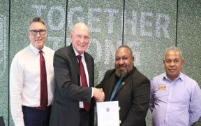 QRL Chairman Bruce Hatcher (2L) and PNGRFL Chairman Sandis Tsaka shake hands after signing a new participation agreement.