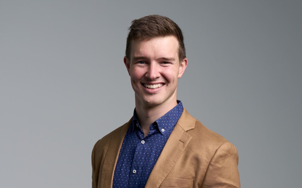 A professional portrait of Urban Intelligence technical director Tom Logan. Tom wears a brown jacket, blue shirt, and is looking directly into the camera.