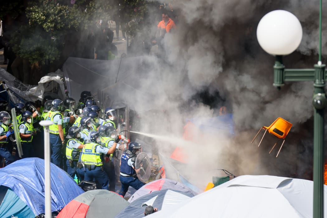 A chair flies through smoke from a fire lit in front of the police while they try to extinguish the blaze