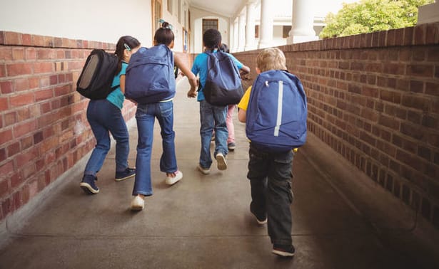 A photo of school kids with one trailing slightly behind
