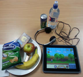 A photo of food and drink placed in front of children while on screens