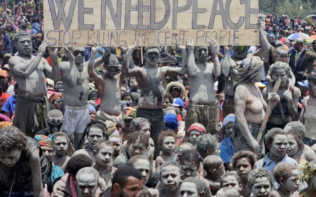 Local villagers hold a placard as they participate in a gathering near the Porgera Gold Mine in Enga province, Papua New Guinea on Sept. 23, 2024, almost one week after police reinforcements were rushed to the area in a bid to quell tribal violence that shuttered the key gold mine