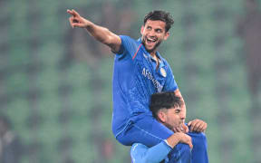 Afghanistan's Azmatullah Omarzai (top) celebrates Afghanistan's victory over England at the Champions Trophy, 2025.