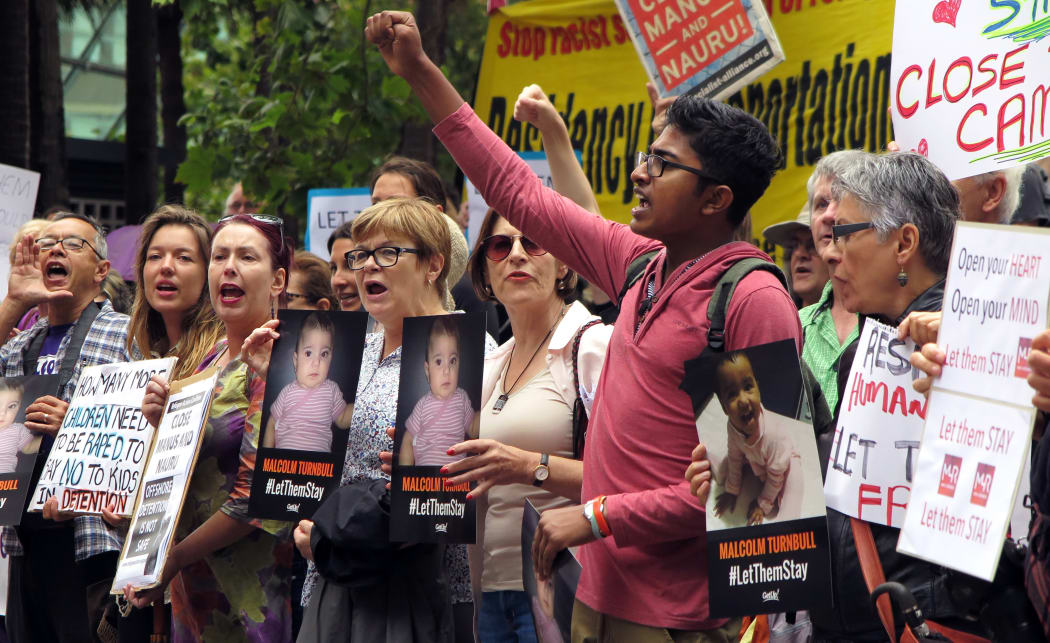 People hold up placards at a protest outside an immigration office in Sydney on February 4, 2016.