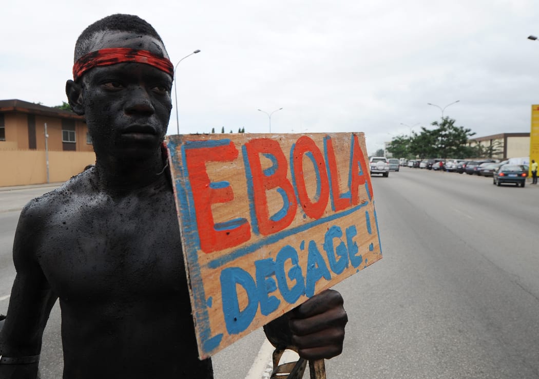 A member of an Ivory Coast artist group hold a placard reading "Ebola, go away".