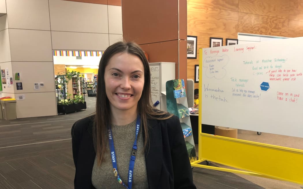 Phoebe Smith smiles at the camera. Behind her is a whiteboard with writing on it.