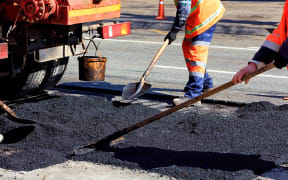 The road workers' working group renews a part of the road with fresh asphalt and levels it for repair in road construction.