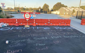 Residents left messages for Auckland Transport in chalk, calling on them to open the road to the public.