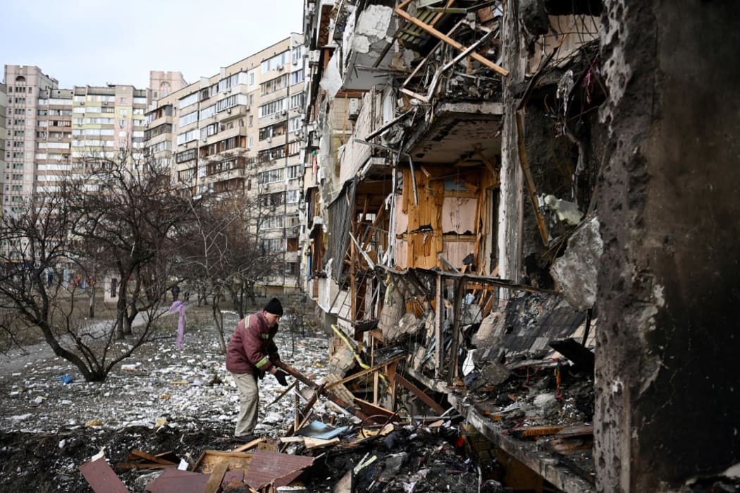 A man clears debris at a damaged residential building at Koshytsa Street, a suburb of the Ukrainian capital Kyiv, where a military shell allegedly hit, on February 25, 2022.