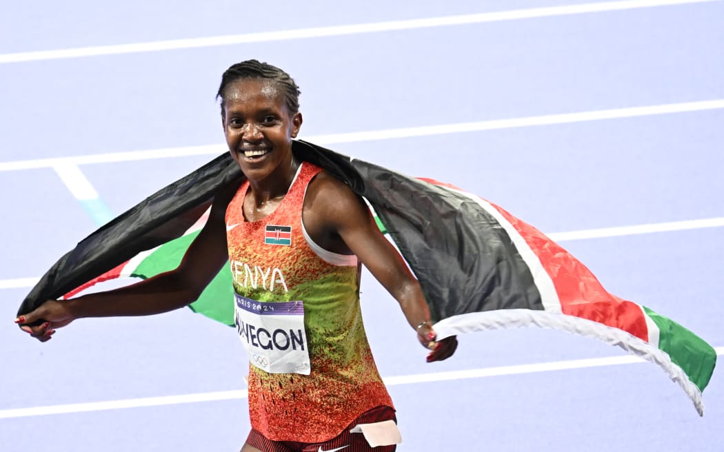 Kenya's Faith Kipyegon celebrates after the women's 5000m final of the athletics event at the Paris 2024 Olympic Games at Stade de France in Saint-Denis, north of Paris, on August 5, 2024. (Photo by MARTIN BERNETTI / AFP)