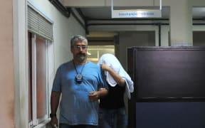 A civil policeman escorts the wife of Greece's ambassador to Brazil Kyriakos Amiridis, Francoise Amiridis, on 30 December in Rio de Janeiro.