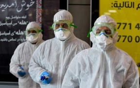 A medical team wearing protective outfit awaits to check Iraqi passengers returning from Iran upon their arrival at the Najaf International Airport on February 21, 2020.