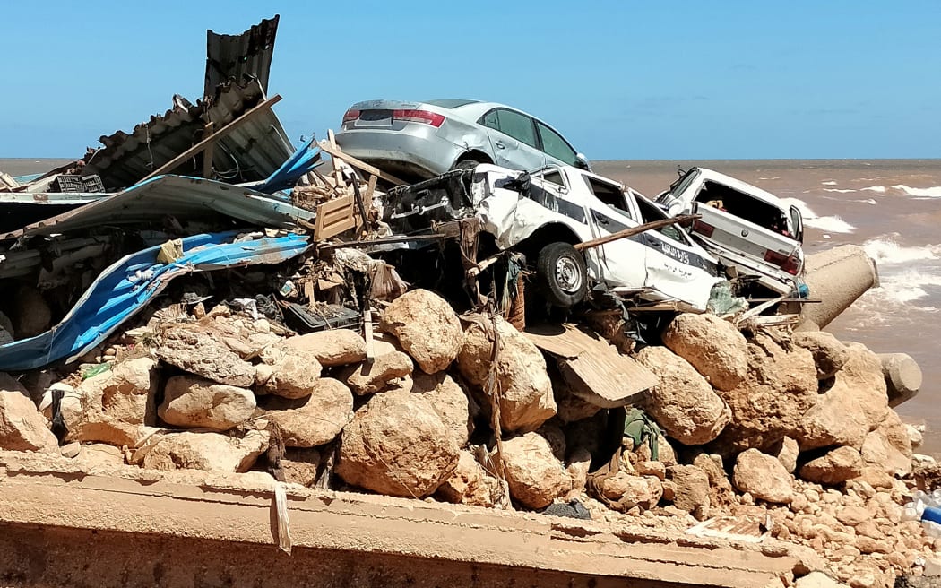 Cars are piled up atop the rubble of a building destroyed in flash floods after the Mediterranean storm "Daniel" hit Libya's eastern city of Derna, on 13 September, 2023. A global aid effort for Libya gathered pace on September 14 after a tsunami-sized flash flood killed at least 4,000 people, with thousands more missing, a death toll the UN blamed in part on the legacy of years of war and chaos.