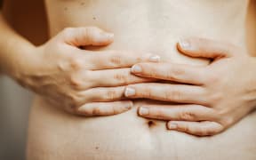 A person grips their bare stomach