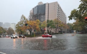Cars drive through surface flooding in central Auckland as rain pelts the region on 9 May 2023.