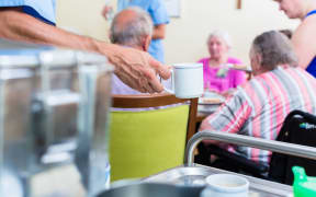 Nurse serving food in rest home for elderly.