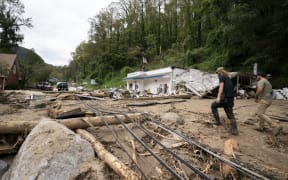 BAT CAVE, NORTH CAROLINA - OCTOBER 1: Men walk along North Carolina Route 9 in the aftermath of Hurricane Helene on October 1, 2024 in Bat Cave, North Carolina. The death toll has topped 140 people across the southeastern U.S. due to the storm, according to published reports, which made landfall as a category 4 storm on Thursday. Millions are without power and the federal government has declared major disasters in areas of North Carolina, Florida, South Carolina, Tennessee, Georgia, Virginia and Alabama, freeing up federal emergency management money and resources for those states, according to the reports.   Sean Rayford/Getty Images/AFP (Photo by Sean Rayford / GETTY IMAGES NORTH AMERICA / Getty Images via AFP)