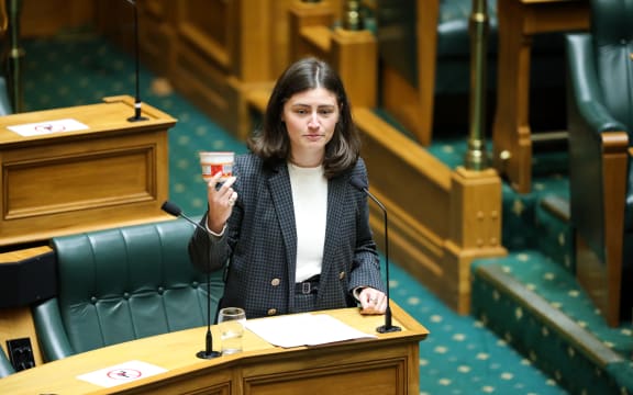Green MP Chloe Swarbrick holds up a cup of instant noodles as an example of what students can afford to eat once they've paid for living costs