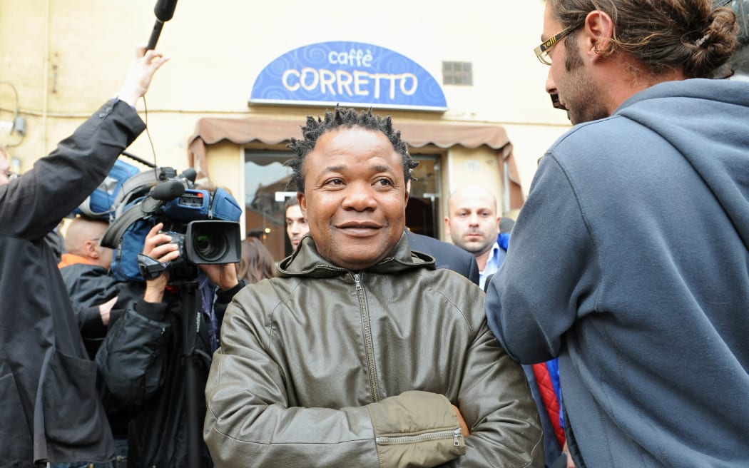 Congolese Patrick Lumumba (C), who was held for two weeks on suspicion of involvement in the murder of a British exchange student, Meredith Kercher  is surrounded by journalists in Perugia on October 27, 2008. Meredith Kercher, 22, a student from Leeds University studying in Perugia as part of the Erasmus exchange programme, was found dead in her Perugia flat on November 1, 2007 with her throat cut. An Italian judge on Tuesday is to issue a first verdict in a whodunnit that has gripped the Italy central town of Perugia for nearly a year since the gruesome murder of a British student. AFP PHOTO / ALBERTO PIZZOLI (Photo by ALBERTO PIZZOLI / AFP)