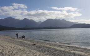 People walk along the shore of Lake Manapouri.