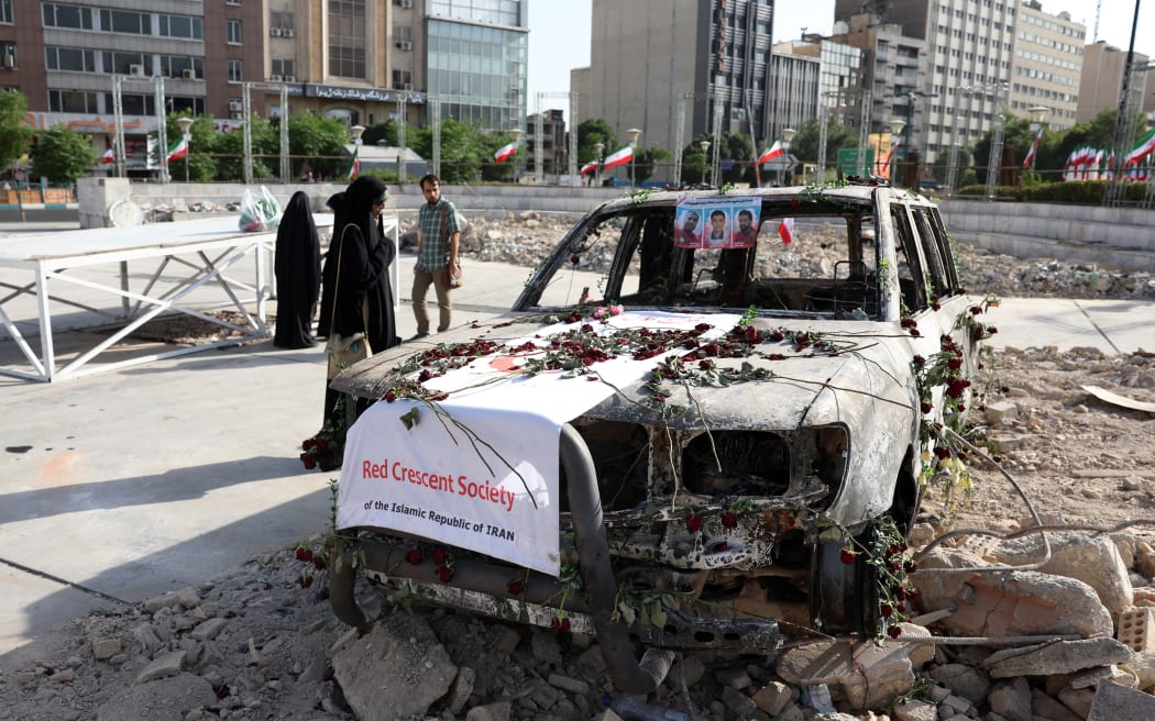 Iranians check an Iranian Red Crescent ambulance that was destroyed during an Israeli strike, displayed in Tehran on 23 June 2025. Israel struck Tehran and Iran fired missiles on 23 June as the war between the longtime foes raged for its 11th day after the United States sent bombers to attack the Islamic republic's nuclear sites.