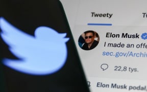 An Elon Musk tweet is displayed on a screen and the Twitter logo is displayed on a phone screen in this illustration photo.