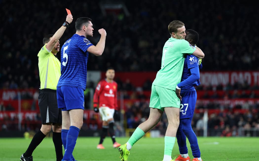 Everton's English goalkeeper #01 Jordan Pickford (2R) separates Everton's Senegalese midfielder #27 Idrissa Gueye (R) from Everton's English defender #05 Michael Keane (2L) as English referee Tony Harrington (L) shows a red card to Gueye during the English Premier League football match between Manchester United and Everton at Old Trafford in Manchester, north west England, on November 24, 2025. (Photo by Darren Staples / AFP) / RESTRICTED TO EDITORIAL USE. NO USE WITH UNAUTHORIZED AUDIO, VIDEO, DATA, FIXTURE LISTS, CLUB/LEAGUE LOGOS OR 'LIVE' SERVICES. ONLINE IN-MATCH USE LIMITED TO 120 IMAGES. AN ADDITIONAL 40 IMAGES MAY BE USED IN EXTRA TIME. NO VIDEO EMULATION. SOCIAL MEDIA IN-MATCH USE LIMITED TO 120 IMAGES. AN ADDITIONAL 40 IMAGES MAY BE USED IN EXTRA TIME. NO USE IN BETTING PUBLICATIONS, GAMES OR SINGLE CLUB/LEAGUE/PLAYER PUBLICATIONS. /