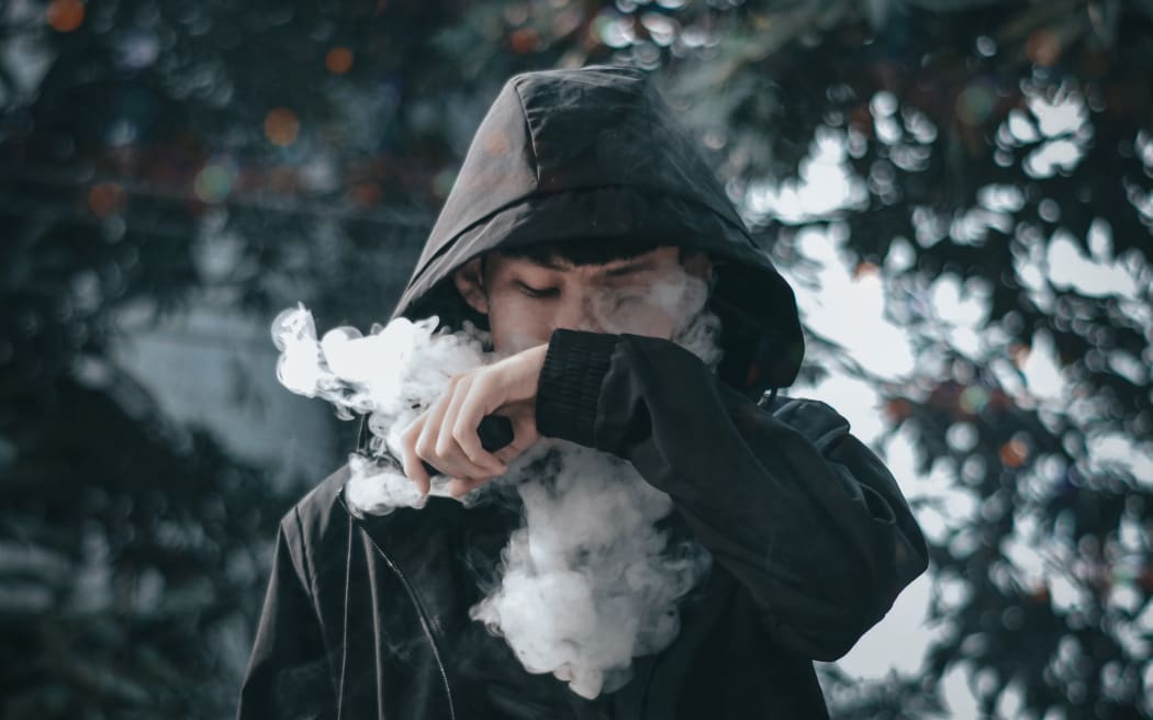A teenager smokes an e-cigarette.