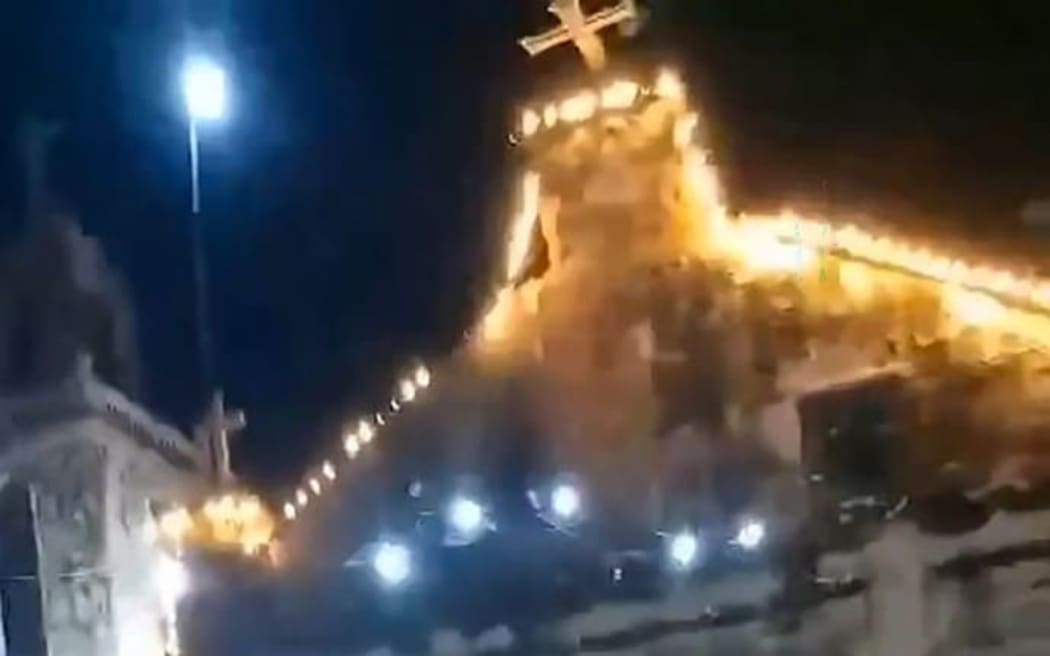 This handout screen grab taken from UGC video footage courtesy of Facebook user Martham Pacilan taken and received on September 30, 2025 shows the cross of a church about to fall owing to earthquake vibrations at the Bantayan Island in central Philippines.