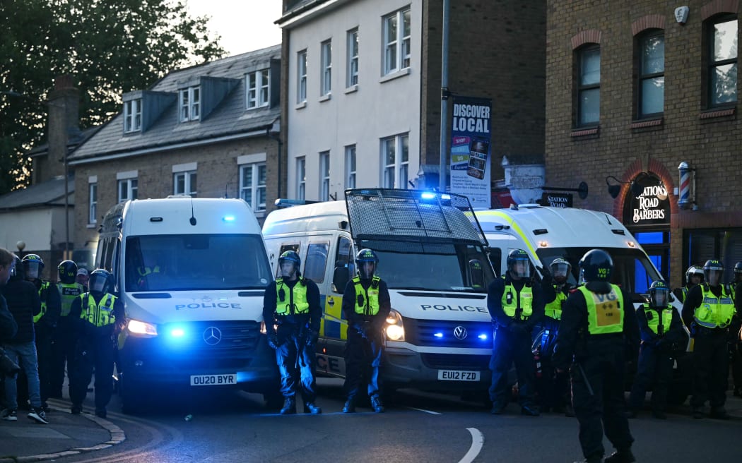 Police officers form a line in the town centre of Epping, northest of London, on July 20, 2025 after protesters march from a demonstration outside The Bell Hotel, believed to be housing asylum seekers after police charged an asylum-seeker with sexual offences earlier this month.  (Photo by JUSTIN TALLIS / AFP)
