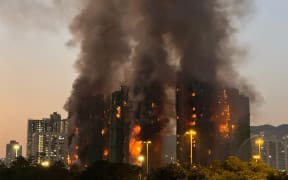 Thick smoke and flames rise as a major fire engulfs several apartment blocks at Wang Fuk Court in Hong Kong's Tai Po district on November 26, 2025. Four people died after multiple blocks in a Hong Kong residential estate went up in flames on November 26, with local media earlier reporting that some residents were trapped. (Photo by Yan ZHAO / AFP)