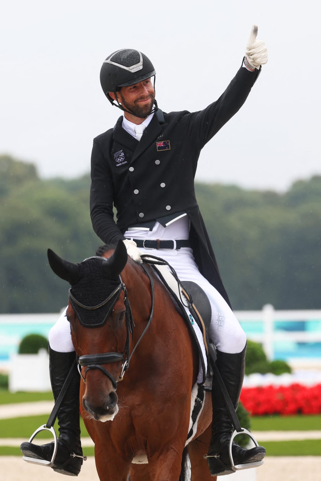 New Zealand's Clarke Johnstone on Menlo Park gives a thumbs-up as he competes in the equestrian dressage during the Paris 2024 Olympic Games at the Chateau de Versailles in Versailles on July 27, 2024. (Photo by Pierre-Philippe MARCOU / AFP)