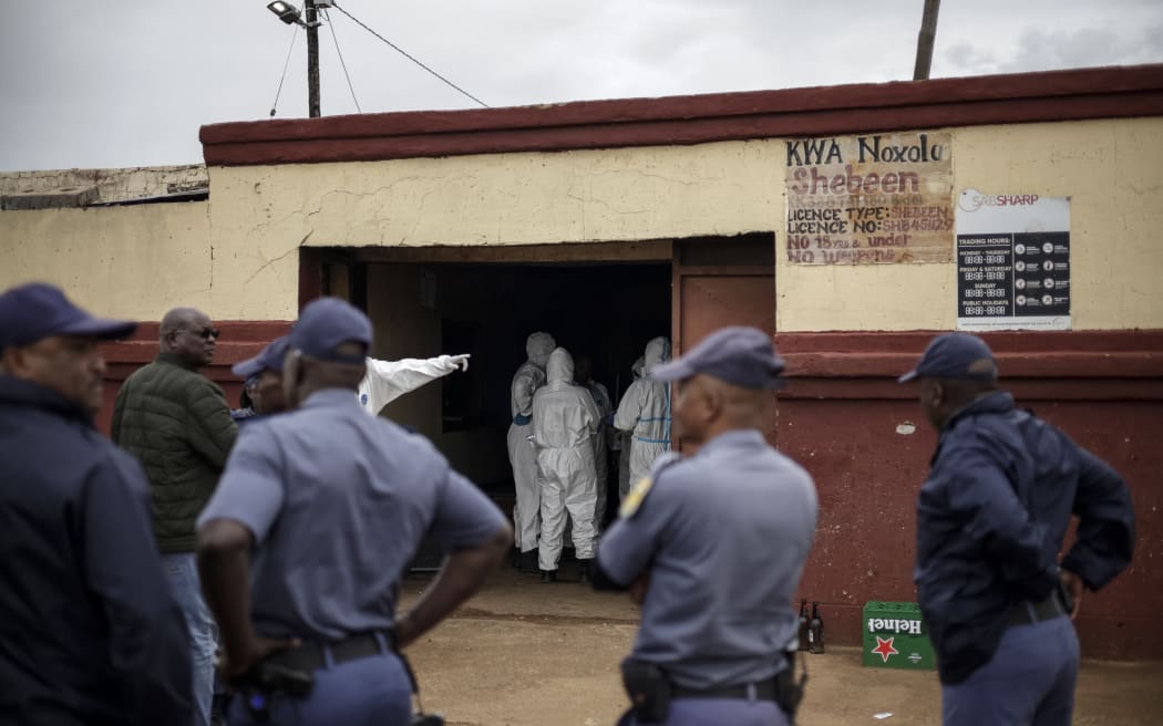South African Police Service (SAPS) officers watch as SAPS Forensic Pathology Services members work at the scene of an attack at a tavern in Bekkersdal on December 21, 2025. Nine people were killed when gunmen opened fire at a bar outside Johannesburg early on December 21, 2025.
Ten more were wounded in the early morning attack at the tavern at Bekkersdal, in a gold mining area around 40 kilometres (25 miles) southwest of the city. (Photo by EMMANUEL CROSET / AFP)