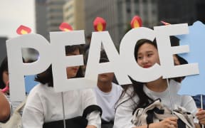South Korean peace group members hold "peace" cardboards during a rally to wish for peace and success at the upcoming summit between US President Donald Trump and North Korea's leader Kim Jong Un
