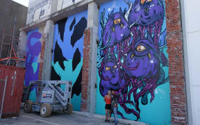 Bobby Hung (right) and assistant Danae Ripley in front of the artist's mural on Gloucester Street.