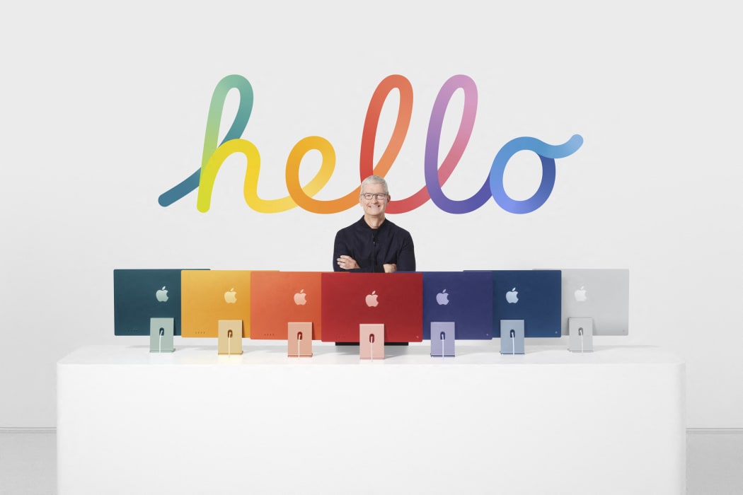 This handout released and taken on April 20, 2021 by Apple inc. shows Apple CEO Tim Cook posing next to the redesigned iMac featuring the company's new in-house M1 chip .